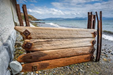 Galler 'in Criccieth plajındaki deniz kıyısını korumak için eski ahşap ağaçlar ve paslı metaller kullanırdı..
