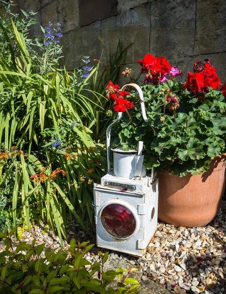 Bahçedeki çiçeklerin arasında Retro demiryolu lambası.