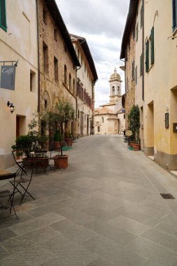 San Quirico d 'Orcia caddesinde kafeler ve arkada Barok Collegiate Kilisesi var. 13.05.2023 San Quirico d 'Orcia, Toskana, İtalya