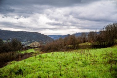 Güneşli bir yaz gününde Dağ Köyü Dağlar 'da küçük bir köyün manzarası. Dağlar arasında tarlaları ve köyleri olan yeşil bir vadi..