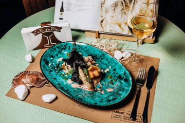 Kremalı karides ve mürekkepbalıklı pirinç cipsi ile doldurulmuş balık filetosu.