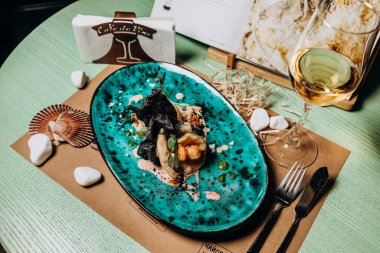 Kremalı karides ve mürekkepbalıklı pirinç cipsi ile doldurulmuş balık filetosu.