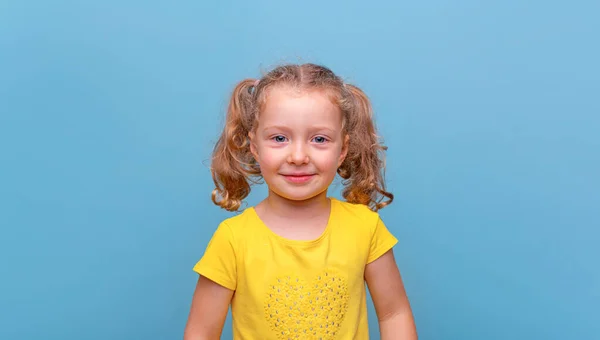 stock image Little girl in a yellow T-shirt on a blue background.