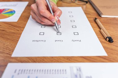 Bir kadın eli, iyi ya da kötü işaret veren bir kontrol listesi ya da sınav kağıdı doldurur..