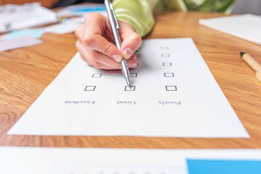 Bir kadın eli, iyi ya da kötü işaret veren bir kontrol listesi ya da sınav kağıdı doldurur..