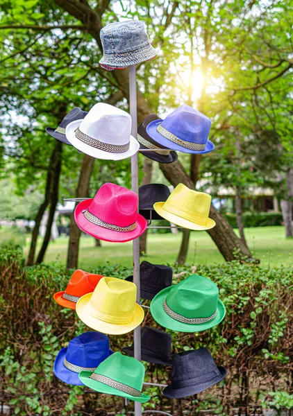 Hanger with hats on the street. Tourist hats of different colors are sold on the street.