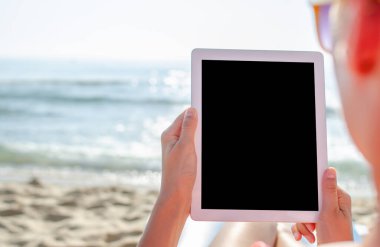 Tabletli bir kadın ya da sahilde akıllı telefon. Tatil.