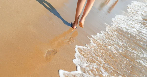 Beautiful female legs walk on the sea sand.