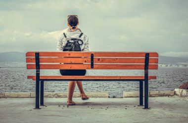 Yalnız bir kadın deniz kenarında ya da gölde bir bankta oturuyor..