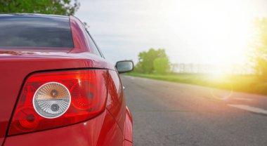 Kırsal bir yolda kırmızı bir araba Güneşli bir günde tarlada..