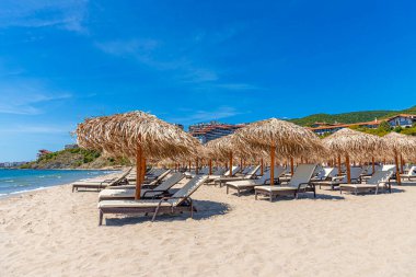 Straw beach umbrellas and sun loungers for relaxing by the sea.