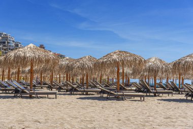 Straw beach umbrellas and sun loungers for relaxing by the sea.