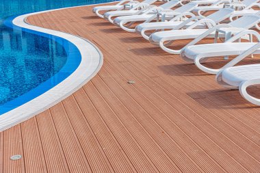 Sun chairs at the pool. Sun loungers by the side of a swimming pool.