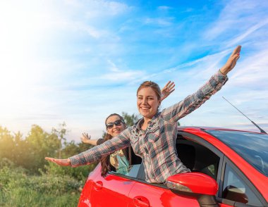 Two young happy girls in a red car. Man and woman in a car.
