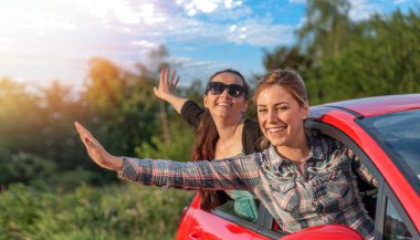 Two young happy girls in a red car. Man and woman in a car.
