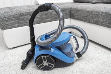 Modern vacuum cleaner in the living room. Vacuum cleaner on the background of the home interior.