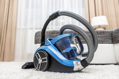 Modern elektrikli süpürge oturma odasında. Evin arka planında elektrik süpürgesi var..