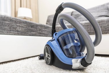 Modern vacuum cleaner in the living room. Vacuum cleaner on the background of the home interior.
