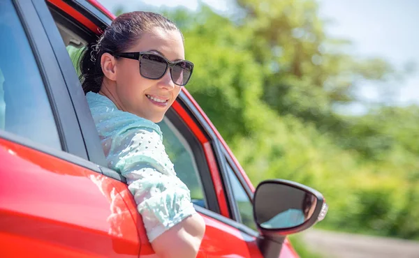 Attractive woman driving a car on a suburban highway.