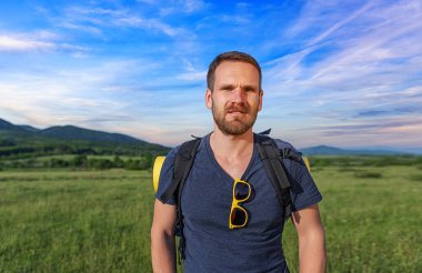 Young male traveler with a backpack in a natural landscape.
