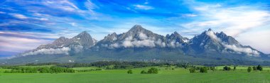 Tatra dağlarının panoramik görüntüsü. Baharda High Tatras 'ın manzarası. Karlı dağ tepeleri ve güzel gökyüzü.