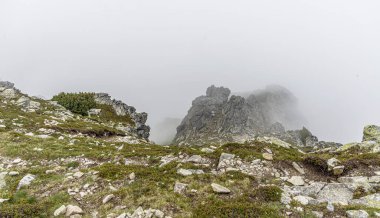Dağ yamacındaki kayalar. Bulutların ve sislerin arasındaki dağ