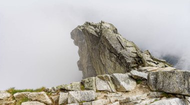 Dağ yamacındaki kayalar. Bulutların ve sislerin arasındaki dağ
