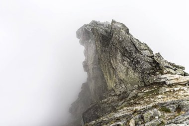 Dağ yamacındaki kayalar. Bulutların ve sislerin arasındaki dağ