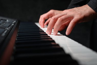 Karanlık bir arkaplanda sentezleyici çalmak. Müzisyen sentezleyiciyi çalıyor..