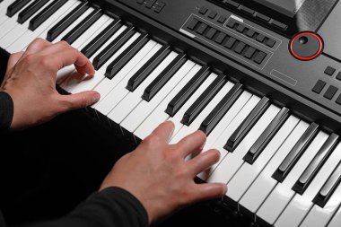 Karanlık bir arkaplanda sentezleyici çalmak. Müzisyen sentezleyiciyi çalıyor..