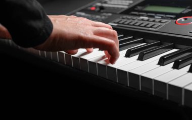 Karanlık bir arkaplanda sentezleyici çalmak. Müzisyen sentezleyiciyi çalıyor..