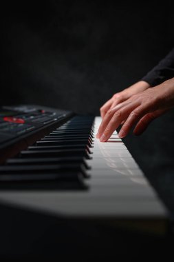 Karanlık bir arkaplanda sentezleyici çalmak. Müzisyen sentezleyiciyi çalıyor..