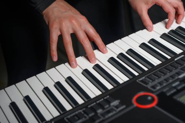 Karanlık bir arkaplanda sentezleyici çalmak. Müzisyen sentezleyiciyi çalıyor..