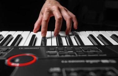 Karanlık bir arkaplanda sentezleyici çalmak. Müzisyen sentezleyiciyi çalıyor..