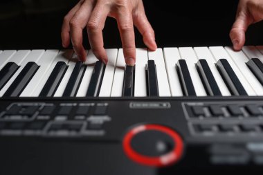 Karanlık bir arkaplanda sentezleyici çalmak. Müzisyen sentezleyiciyi çalıyor..