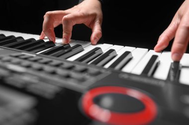 Karanlık bir arkaplanda sentezleyici çalmak. Müzisyen sentezleyiciyi çalıyor..