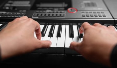 Karanlık bir arkaplanda sentezleyici çalmak. Müzisyen sentezleyiciyi çalıyor..