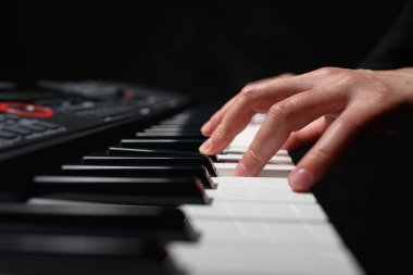 Karanlık bir arkaplanda sentezleyici çalmak. Müzisyen sentezleyiciyi çalıyor..