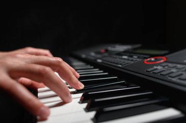 Karanlık bir arkaplanda sentezleyici çalmak. Müzisyen sentezleyiciyi çalıyor..