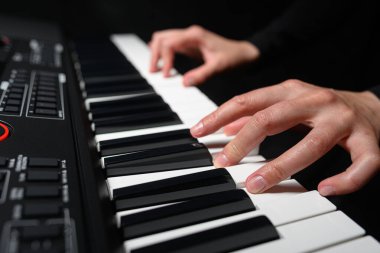 Karanlık bir arkaplanda sentezleyici çalmak. Müzisyen sentezleyiciyi çalıyor..