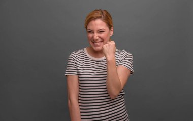 Gri arka planda gülümseyen kız, kollarını göğsünde kavuşturdu..