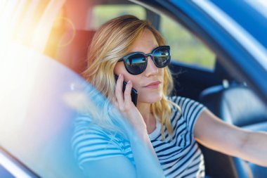 Araba sürerken akıllı telefon kullanan genç güzel kadın