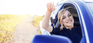 Kadın şoför arabanın anahtarını gösteriyor. Araba satın alma ya da kiralama.