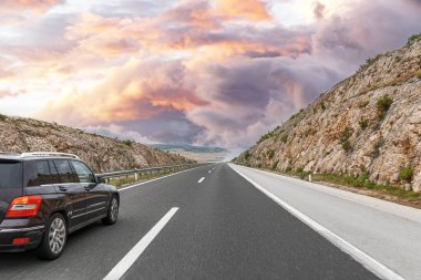 Güzel bir bölgede, otobanda koyu renk bir araba..