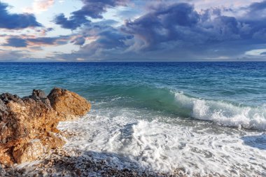 Deniz sörfü. Gün batımında taştan bir plajı olan resim gibi bir sahil..