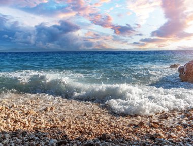 Deniz sörfü. Gün batımında taştan bir plajı olan resim gibi bir sahil..