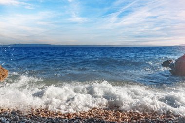 Deniz sörfü. Gün batımında taştan bir plajı olan resim gibi bir sahil..