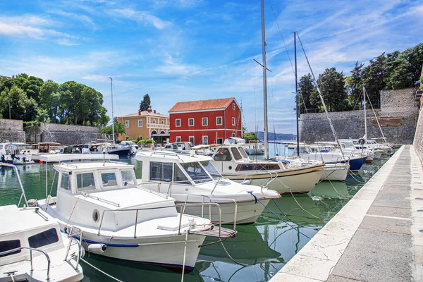 Balıkçılar kırmızı evde ve limanda tekneler var. Hırvatistan ve Zadar.