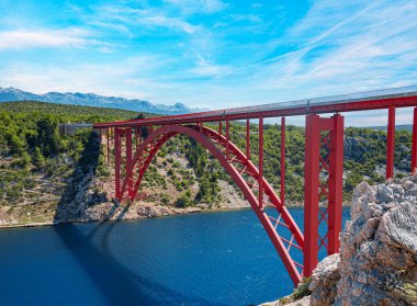Dağların arka planında bir yolu olan demir kemer köprüsü..