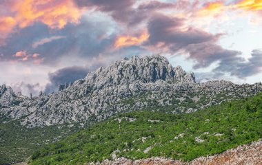 Kayalık dağ manzarası ve zıt bulutlu gökyüzü. Hırvatistan